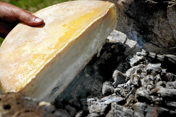 Raclette cheese melting near hot coals